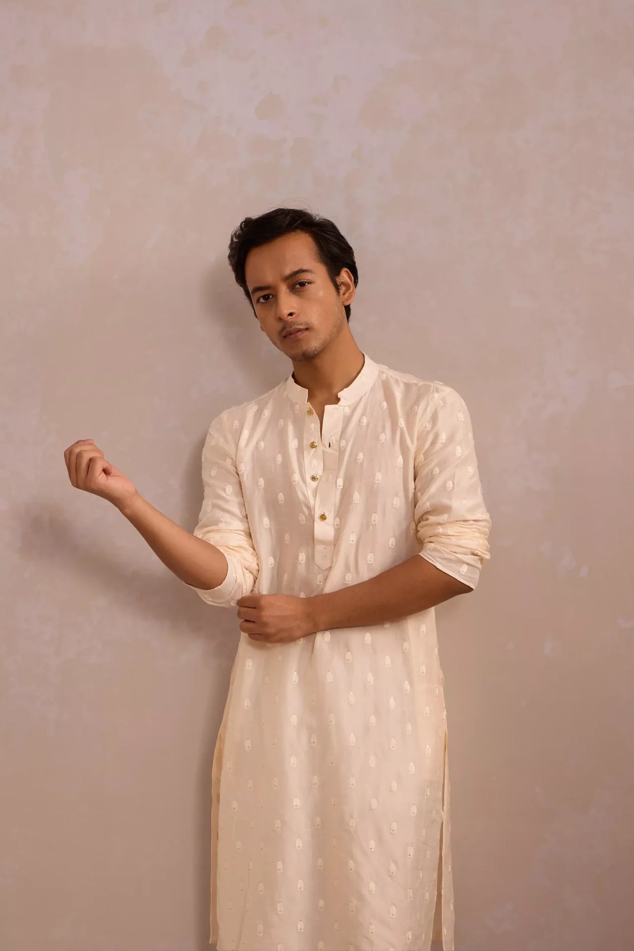 Man wearing a light-colored kurta against a plain background